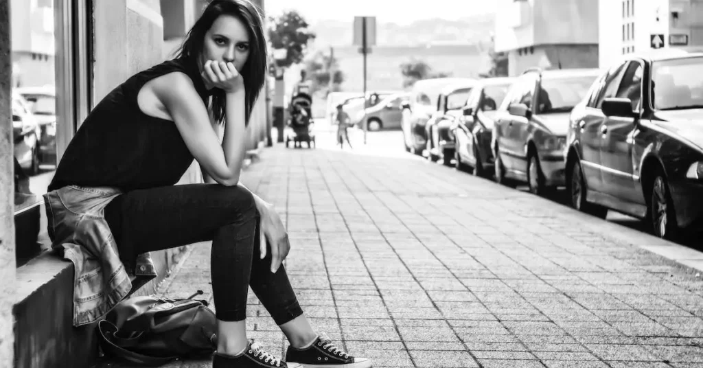 woman sitting on the side of a street as a female pose reference